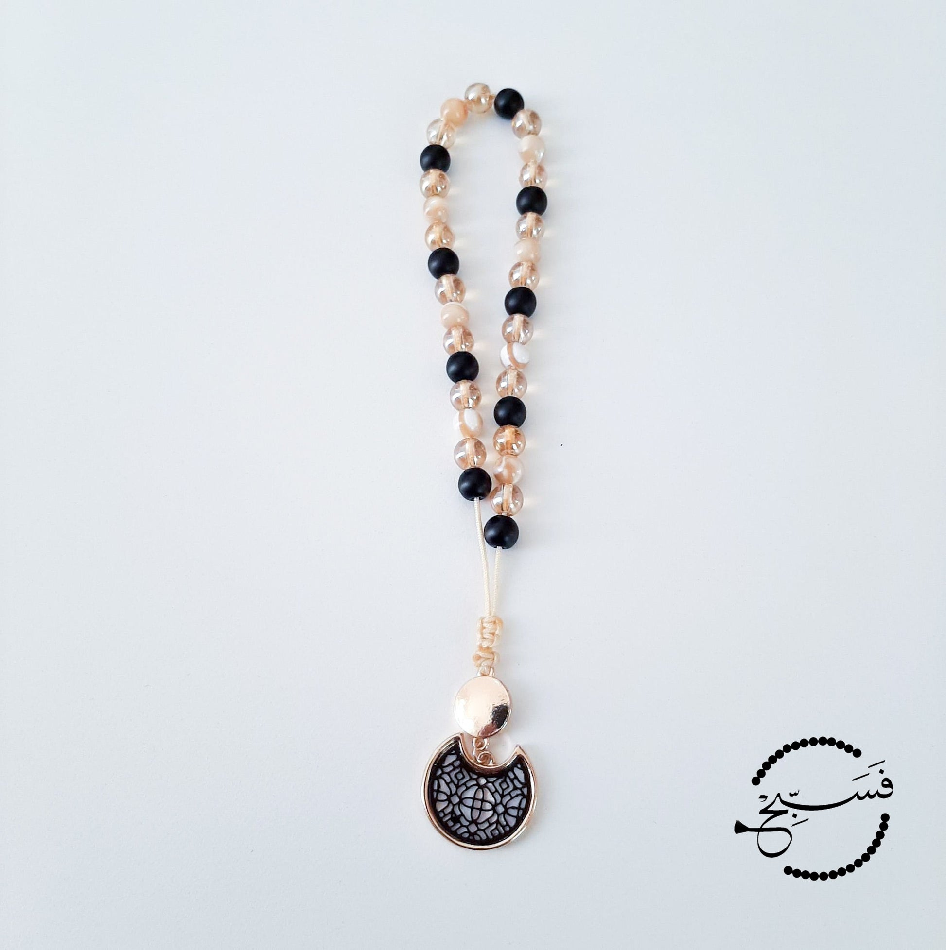 Natural trochus shell with matte black and gold beads, with a geometric design pendant.  Features an adjustable knot.  33 beads (6mm beads)