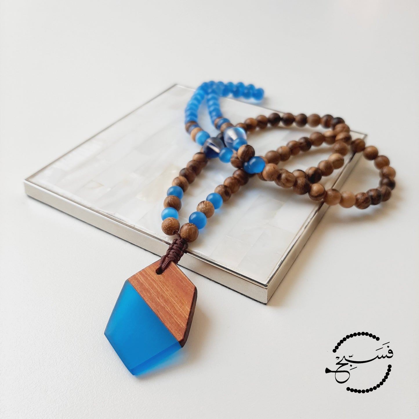 Angular resin and wood pendant with blue cat-eye and wood beads.  Packaged in a luxurious pouch and a gift box.  99 beads