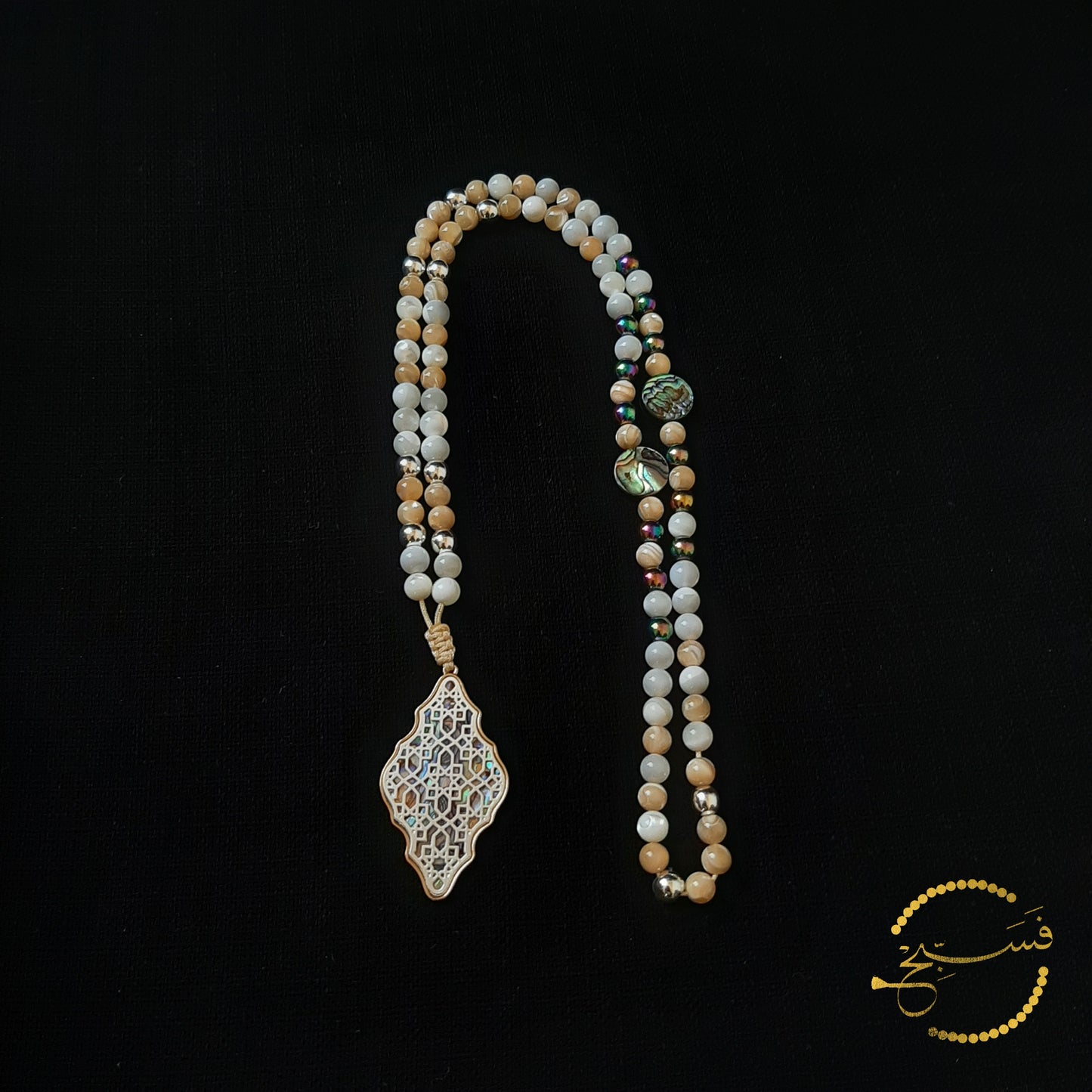 The geometric pattern, reminiscent of Islamic art, over an abalone shell makes a really attractive, silver-finish, pendant. White and caramel shades of trochus shell beads contrast beautifully with the greens of the abalone and hematite beads used sparingly in this tasbih.    Packaged in a luxurious pouch and a gift box.  99 beads